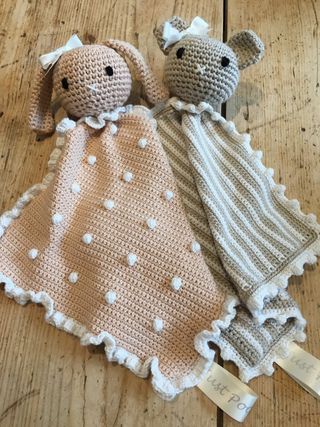 two crocheted stuffed animals laying on top of a wooden floor next to each other