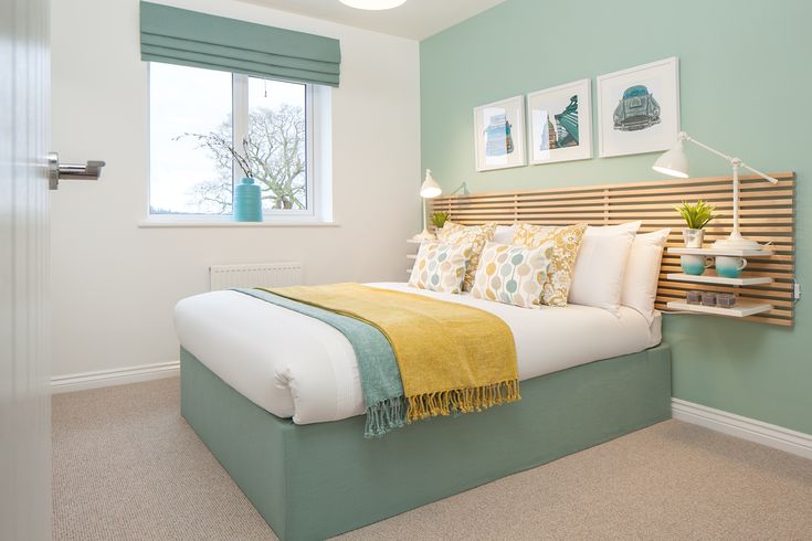 a bedroom with green walls and white bedding, two framed pictures on the wall