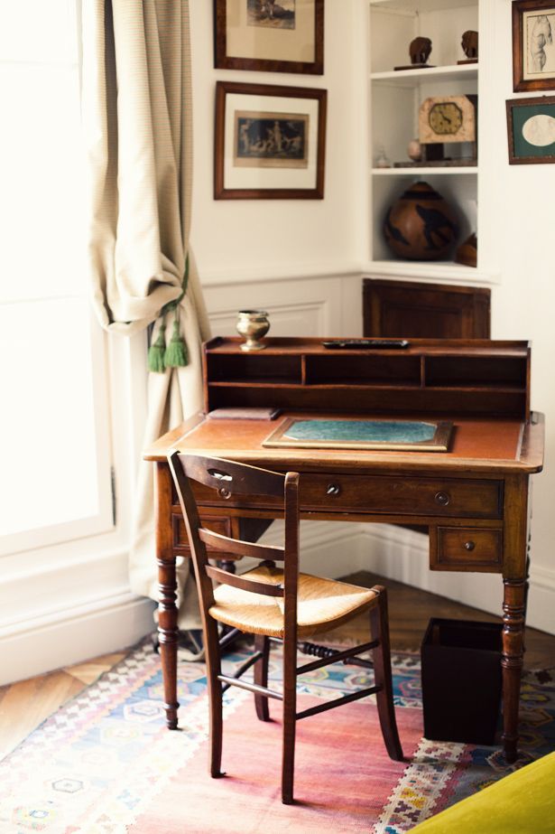 an old desk in the corner of a room with pictures on the wall above it