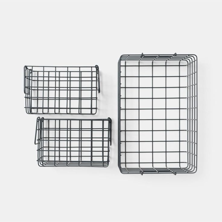 three metal baskets sitting next to each other on top of a white surface with one basket in the middle