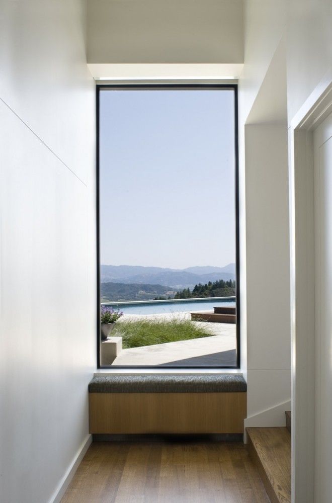 an empty room with a bench and large window overlooking the water in front of it