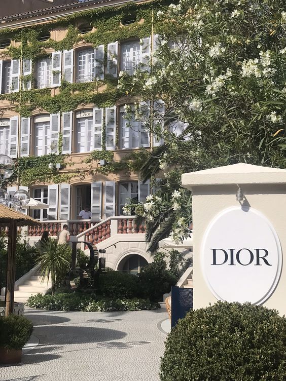 the entrance to dior's garden in front of a building with white flowers on it