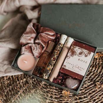 an open box with candles, soaps and other items in it on a wicker table