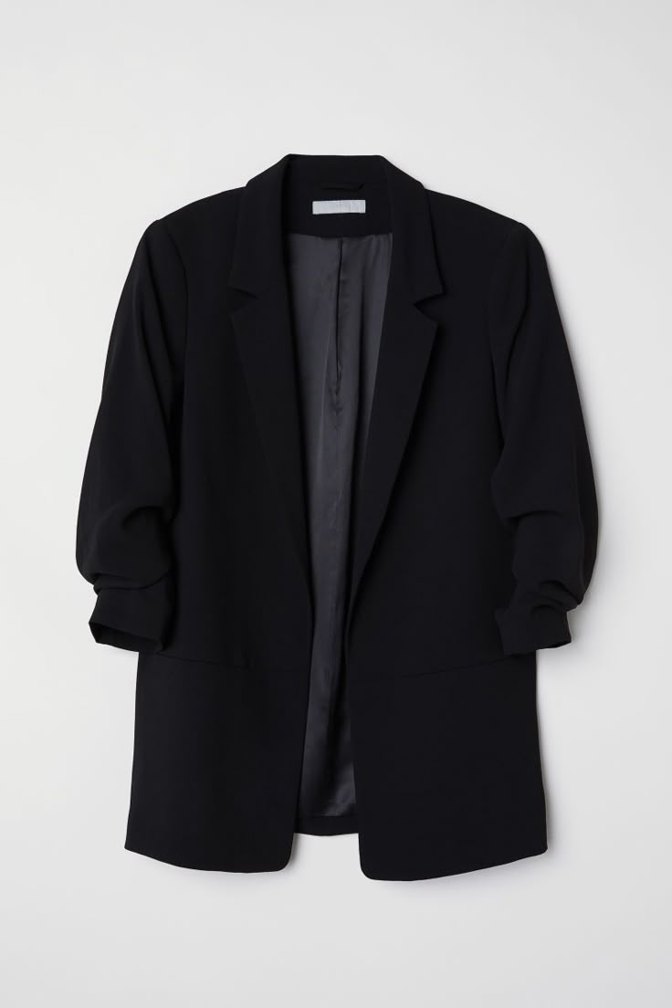 a black blazer jacket hanging on a wall with the back button down and buttons undone