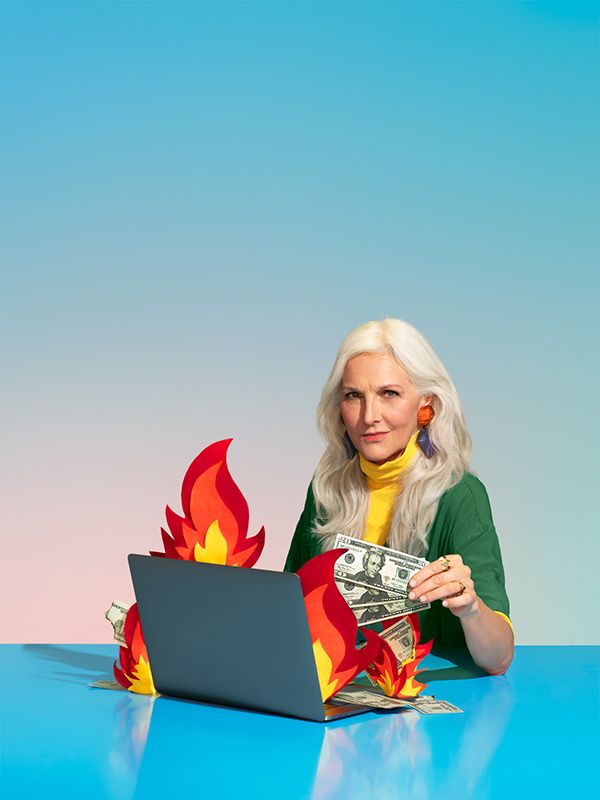 a woman sitting in front of a laptop computer on top of a table with money