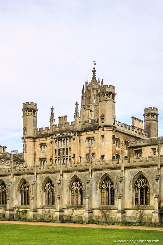 an old building with many windows and towers on the top floor, in front of a green lawn