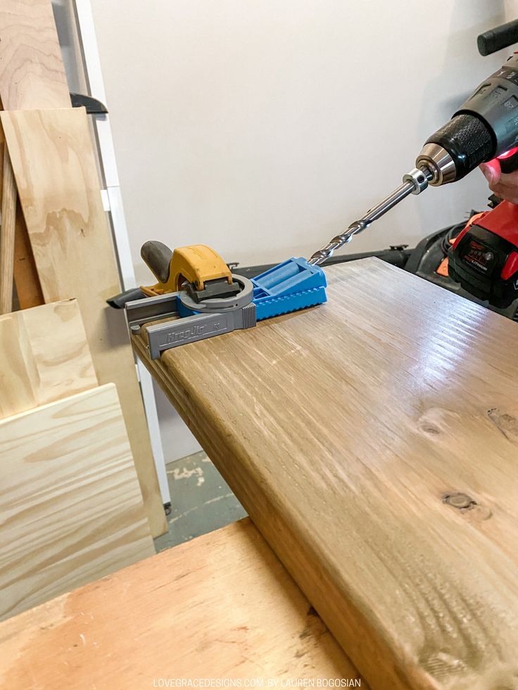 a person using a power drill on a wooden table