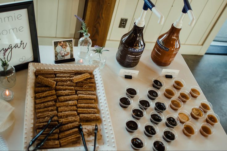 a table topped with lots of different types of donuts and syrups on top of it