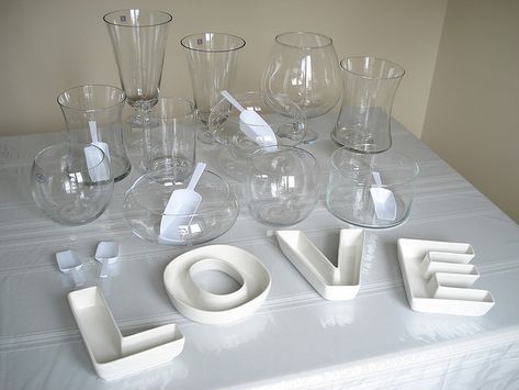 a table topped with lots of glass cups and glasses next to the word love spelled out in white letters