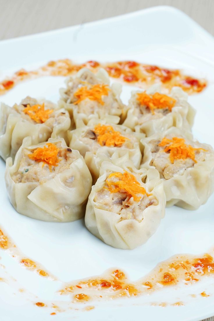 some dumplings are on a white plate with orange zest sprinkles