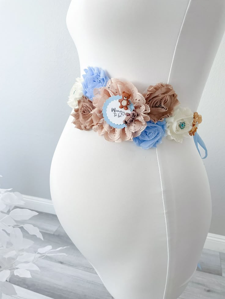 a white mannequin with blue and pink flowers on it's waist,