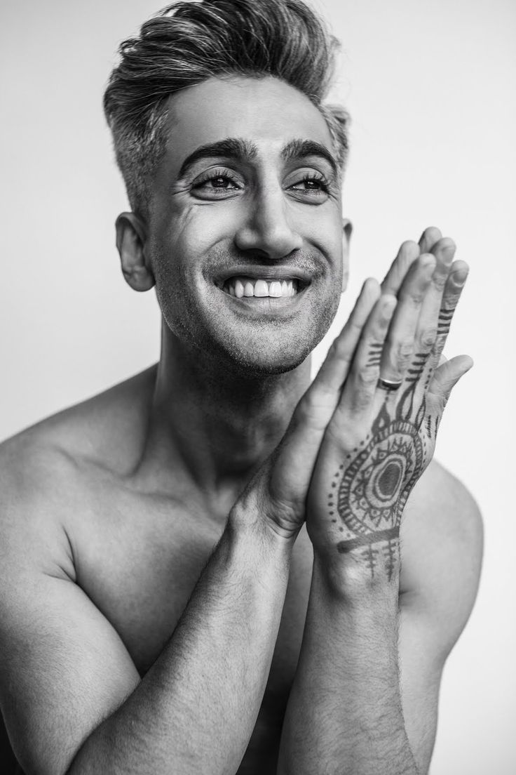 a man smiling and holding his hands in front of his face with tattoos on it