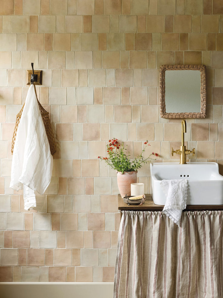 a white sink sitting under a bathroom mirror next to a wooden shelf with towels on it