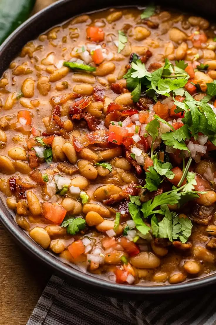 a bowl filled with beans and cilantro on top of a wooden table