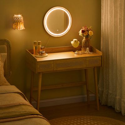 a small table with a mirror on it next to a bed and a lamp in the corner