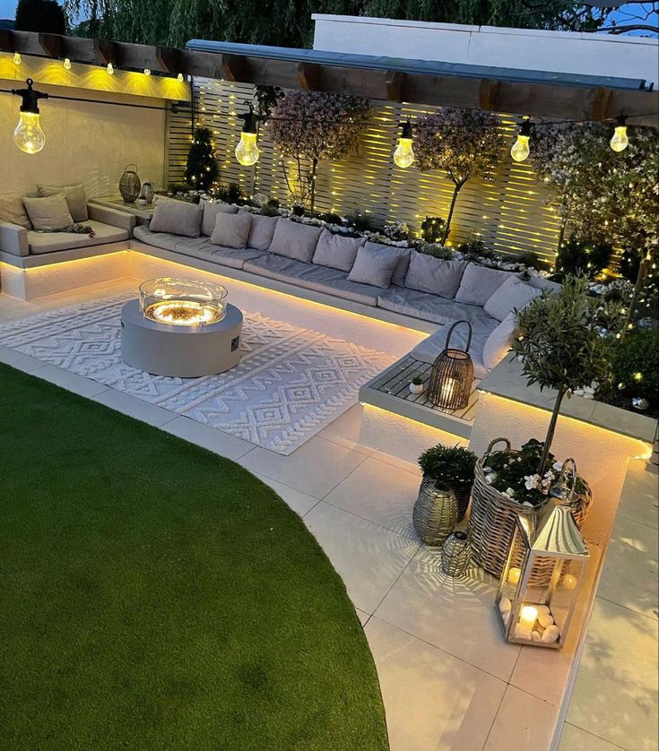 an outdoor living area is lit up at night with lights on the couches and tables