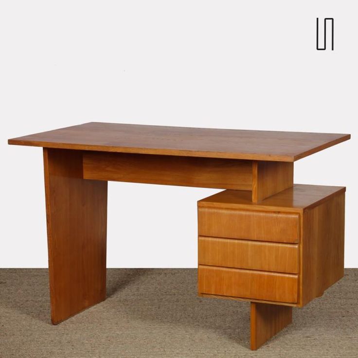 a wooden desk with two drawers underneath it on carpeted floor next to white wall