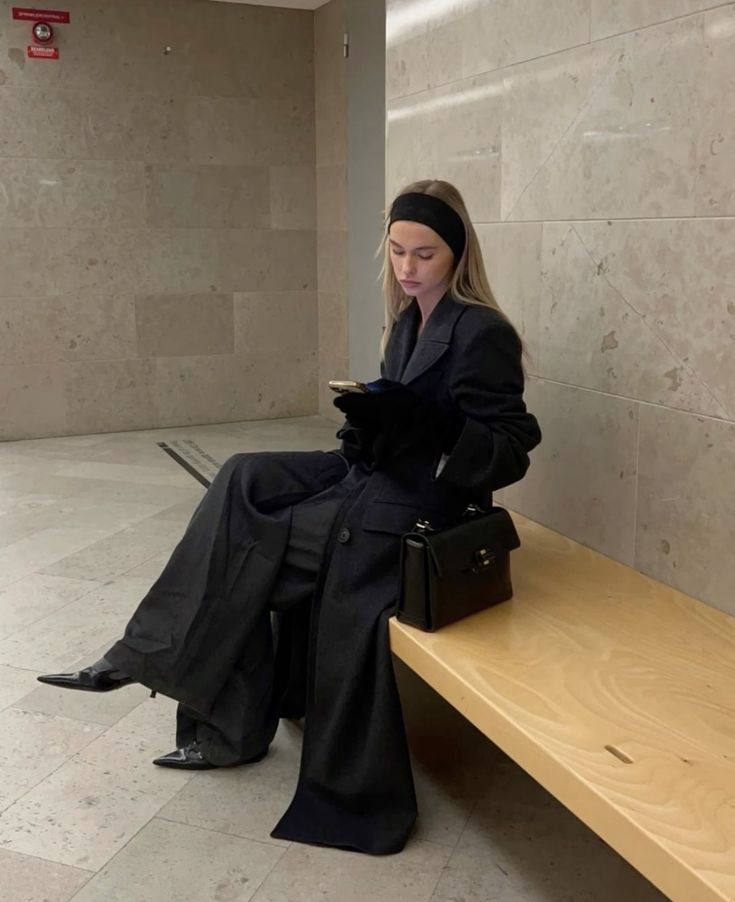 a woman sitting on top of a wooden bench