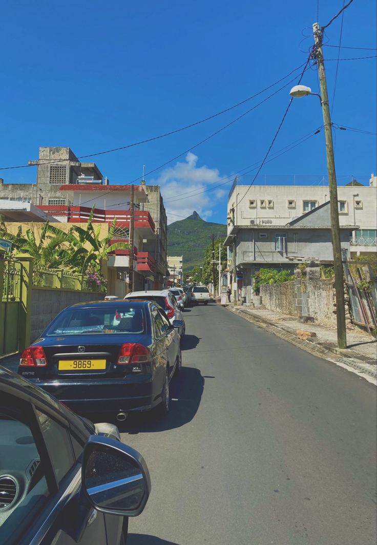 cars are parked on the side of the road in front of houses and power lines