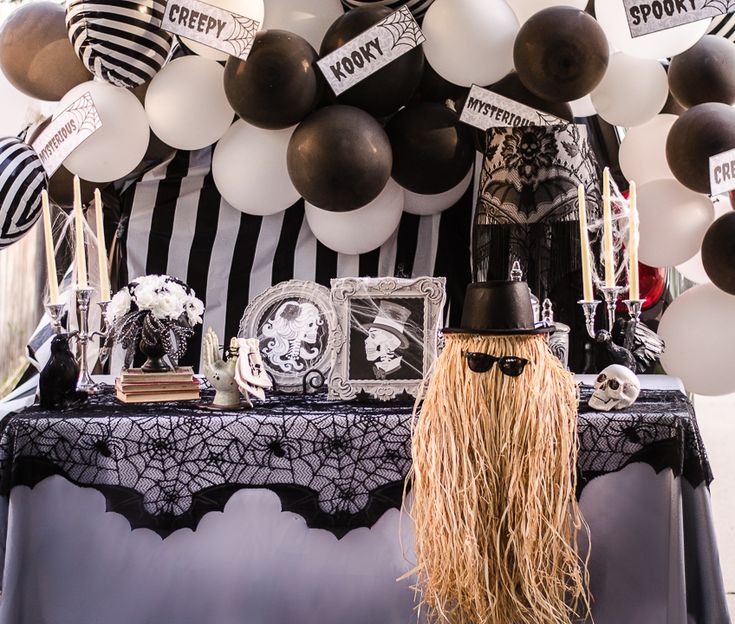 a table topped with balloons and decorations next to a black and white striped wallpaper