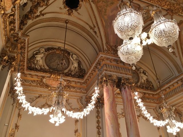 chandeliers hanging from the ceiling in an ornately decorated room