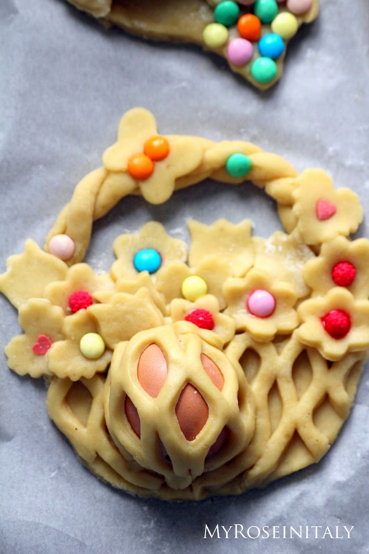 two cookies decorated with candy and candies on top of a sheet of wax paper