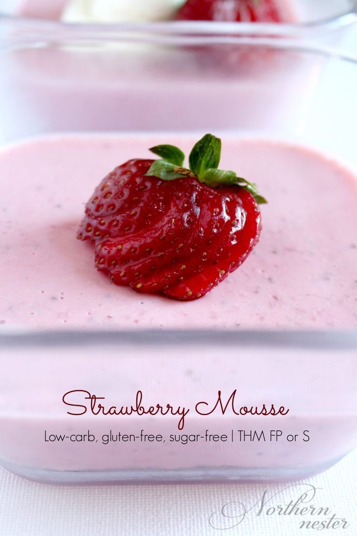 strawberry mousse in a glass dish with two strawberries on top