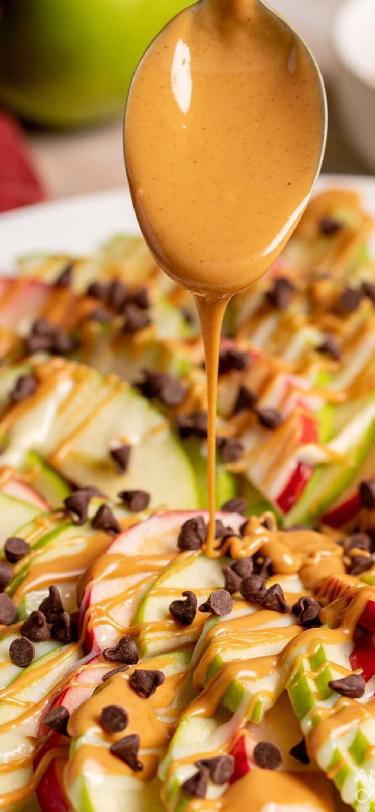 caramel sauce being drizzled over apple slices with chocolate chips on top