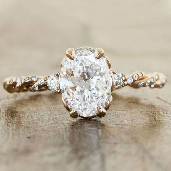 a close up of a ring with a diamond on the top and an oval shaped stone in the middle