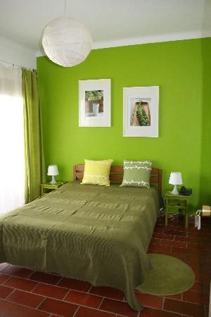 a bedroom with green walls and red tile flooring