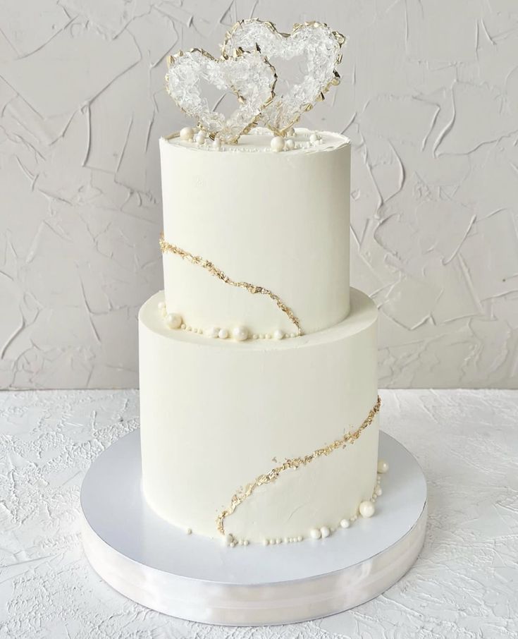 a white wedding cake with two hearts on top