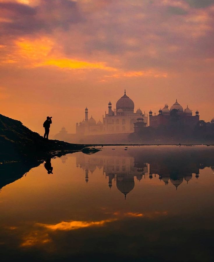 a person standing on the edge of a body of water with a building in the background