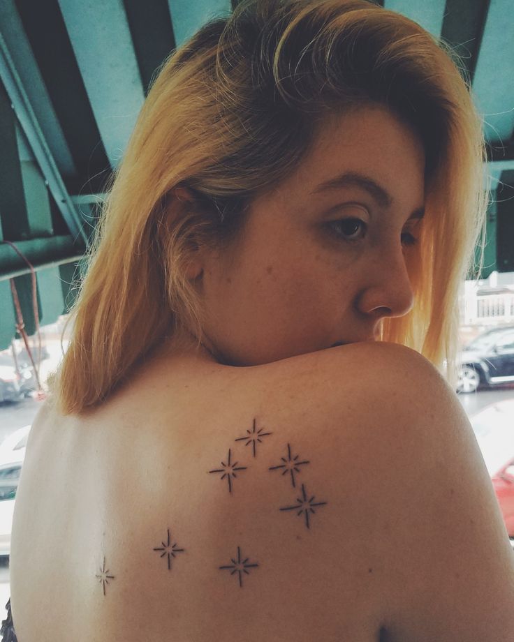 a woman with a star tattoo on her upper back shoulder and arm, looking down at the ground