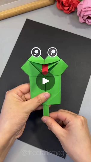 someone is making a frog out of paper and holding it up to the viewer's face