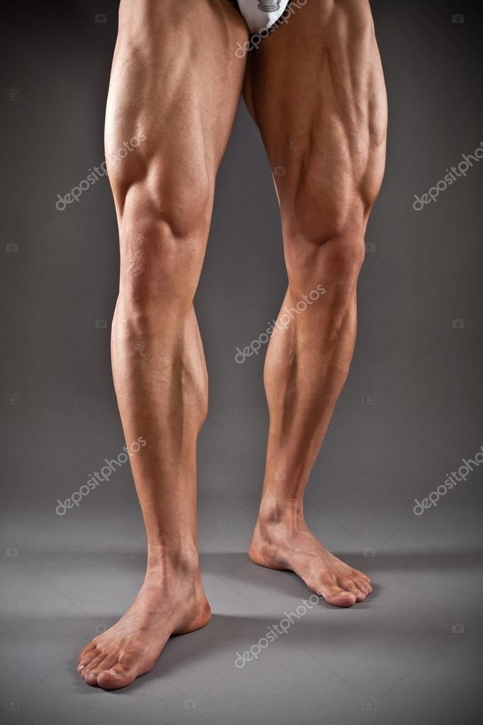 the legs and ankles of a man with no shirt on, in front of a gray background