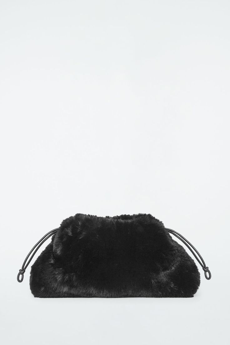 This contemporary bucket-style clutch is crafted from texture-rich faux fur in a subdued black tone. It's shaped with knotted drawstrings at either side that create an exaggerated, softly gathered profile and has a slender leather shoulder strap. A better alternative to conventional polyester, recycled polyester is made from pre‐ and post‐consumer waste  Shell: 100% Recycled polyester. Detailing: 100% Leather. Lining: 50% Cotton, 50% Recycled cotton. Excluding trims Height: 10.23", Width: 14.96" Belted Cape, Accessories Bags Shoes, Belt Jewelry, Women Magazines, Women Accessories Bags, Recycled Cotton, Trending Accessories, Blouse And Skirt, Faux Fur