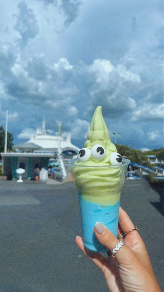 a hand holding an ice cream cone with googly eyes