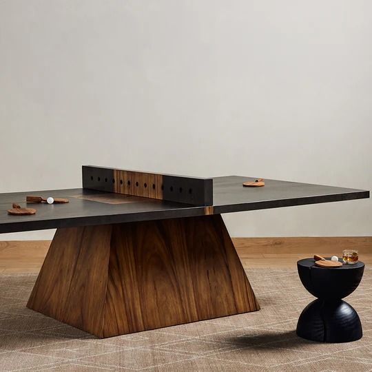 a ping pong table sitting on top of a wooden floor next to a black stool