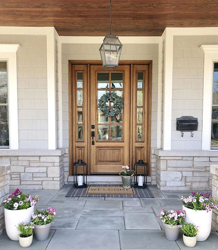 two planters on the front steps of a house with flowers in them and a lantern hanging from the ceiling