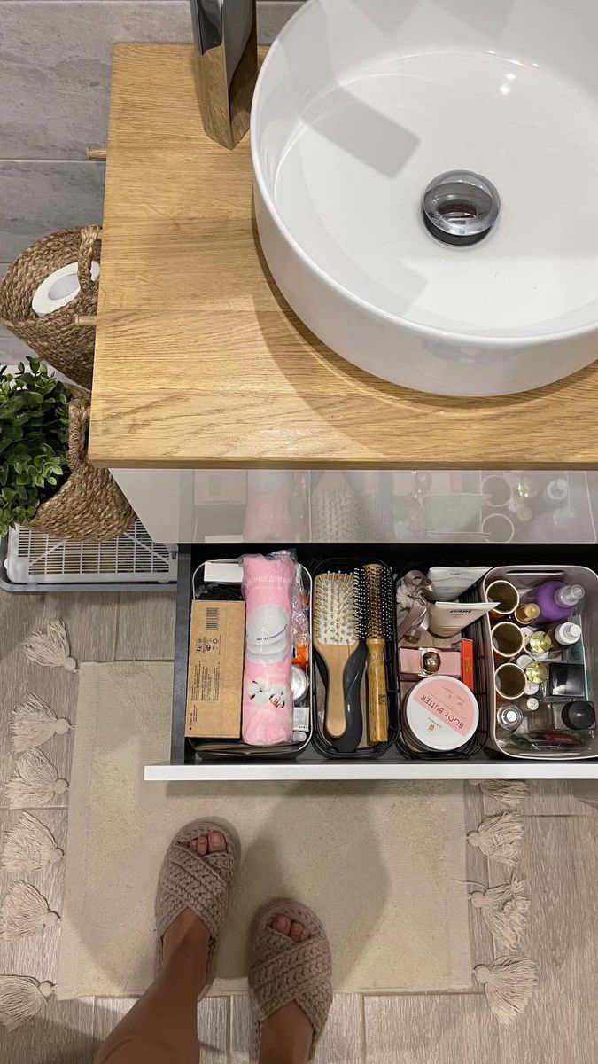 a person standing in front of a sink under a counter top with various items on it