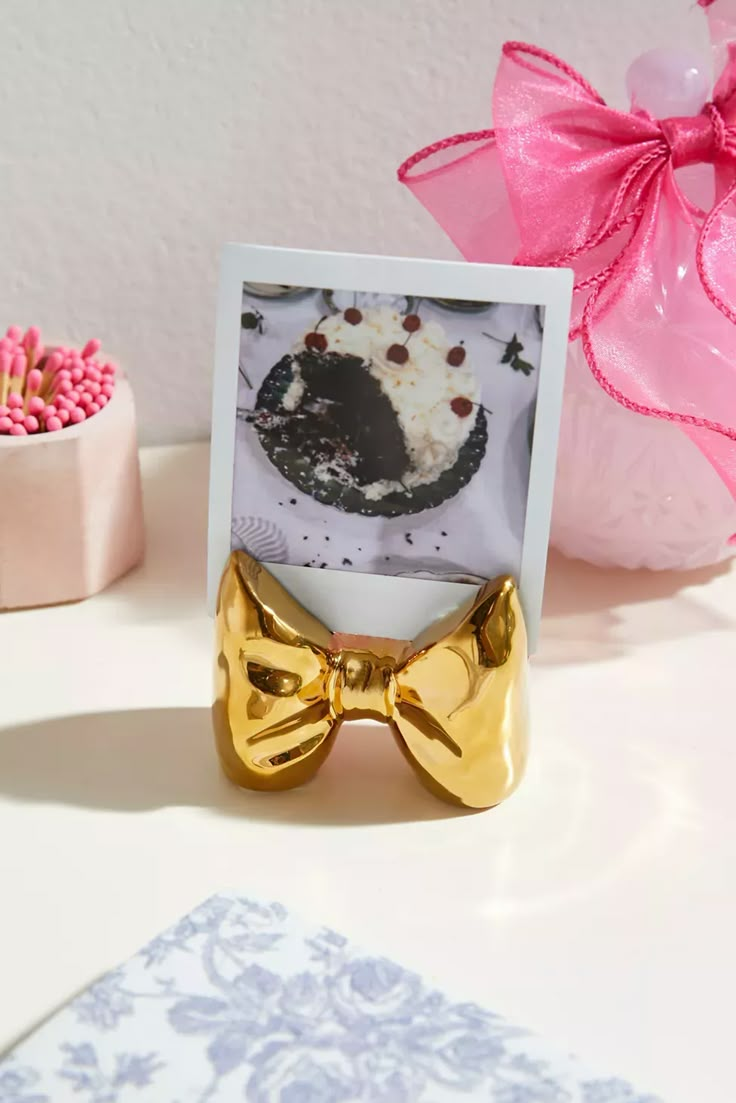 a bow tie is sitting next to a card with a cake on it and pink flowers in the background