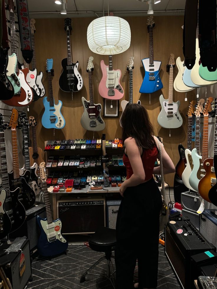 a woman standing in front of guitars and amps