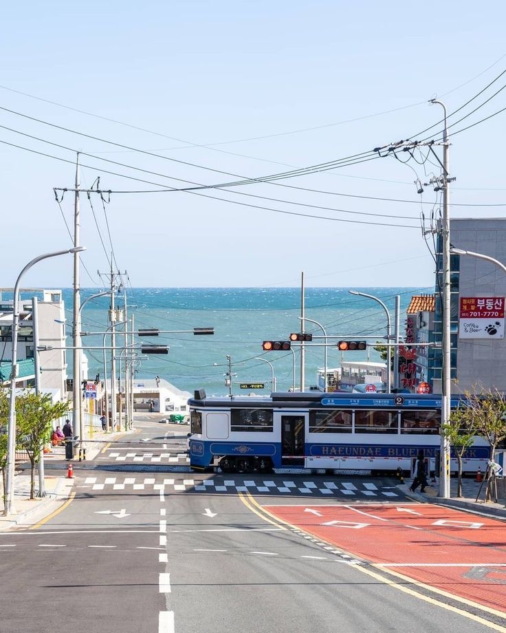 an electric train is traveling down the road by the ocean