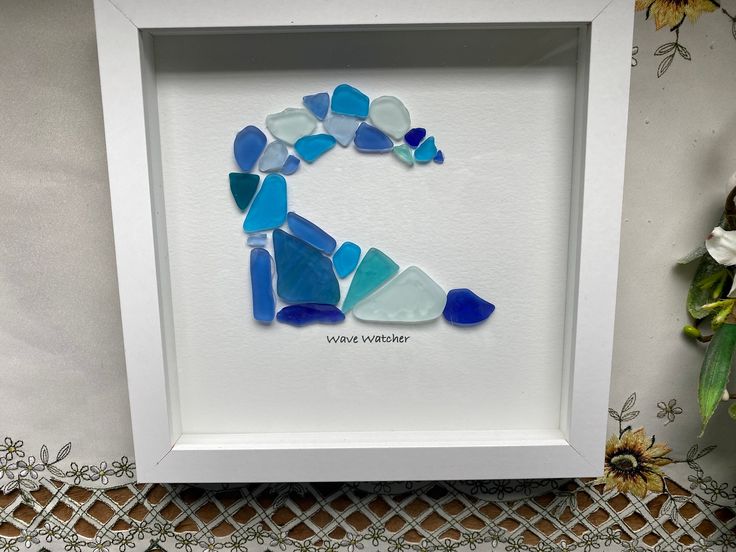 a white frame with blue and green sea glass in the shape of a letter z