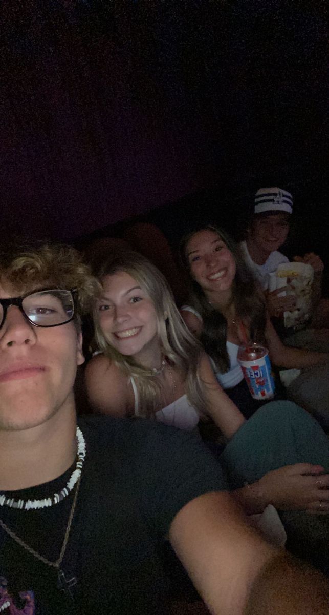 a group of young people sitting next to each other on a couch in a dark room