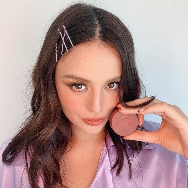 a young woman is holding up a coin to her face