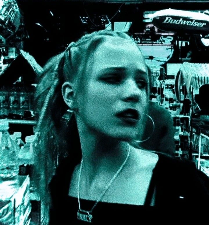 a woman with dreadlocks in a store looking at the camera while talking on her cell phone