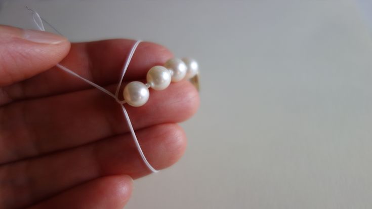 a person holding three pearls in their left hand and string attached to the bead