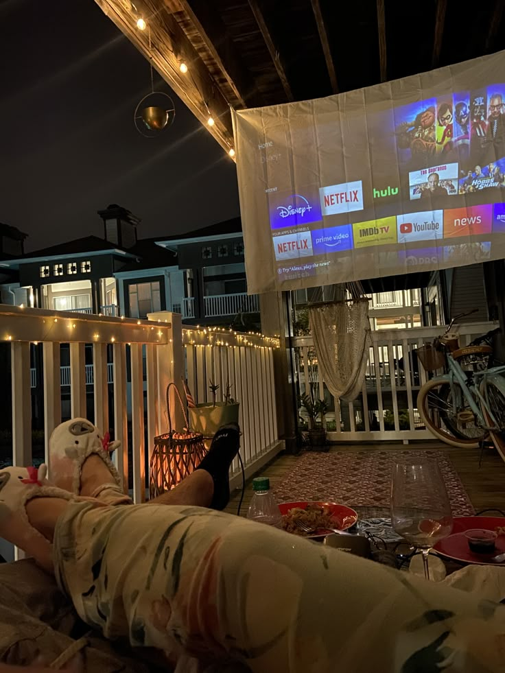 a person laying on a couch in front of a large screen with people watching it