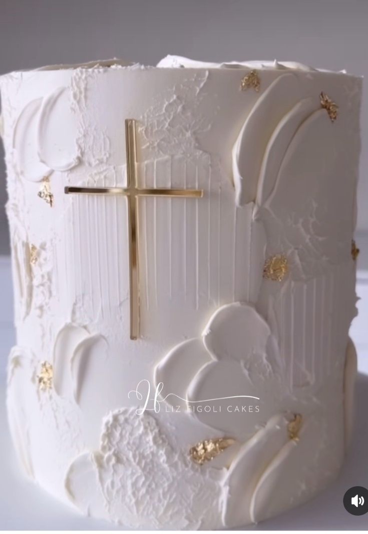 a white cake with gold decorations and a cross on top